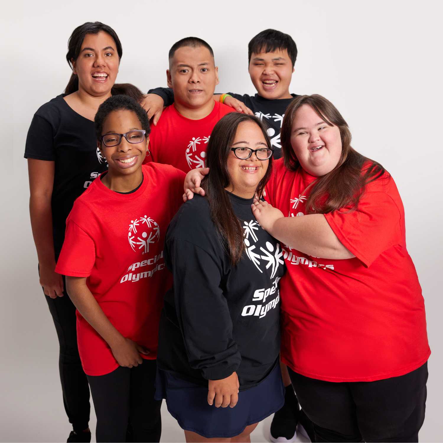 Group of people wearing Special Olympics shirts posing together on a white background